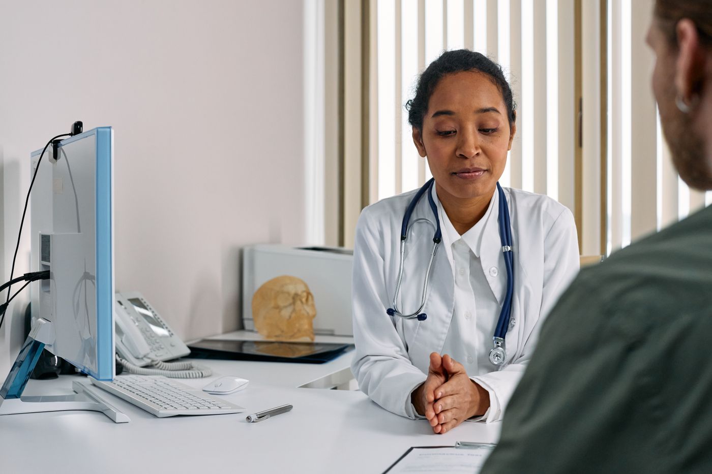 Médica conversando con una persona en un consultorio luminoso